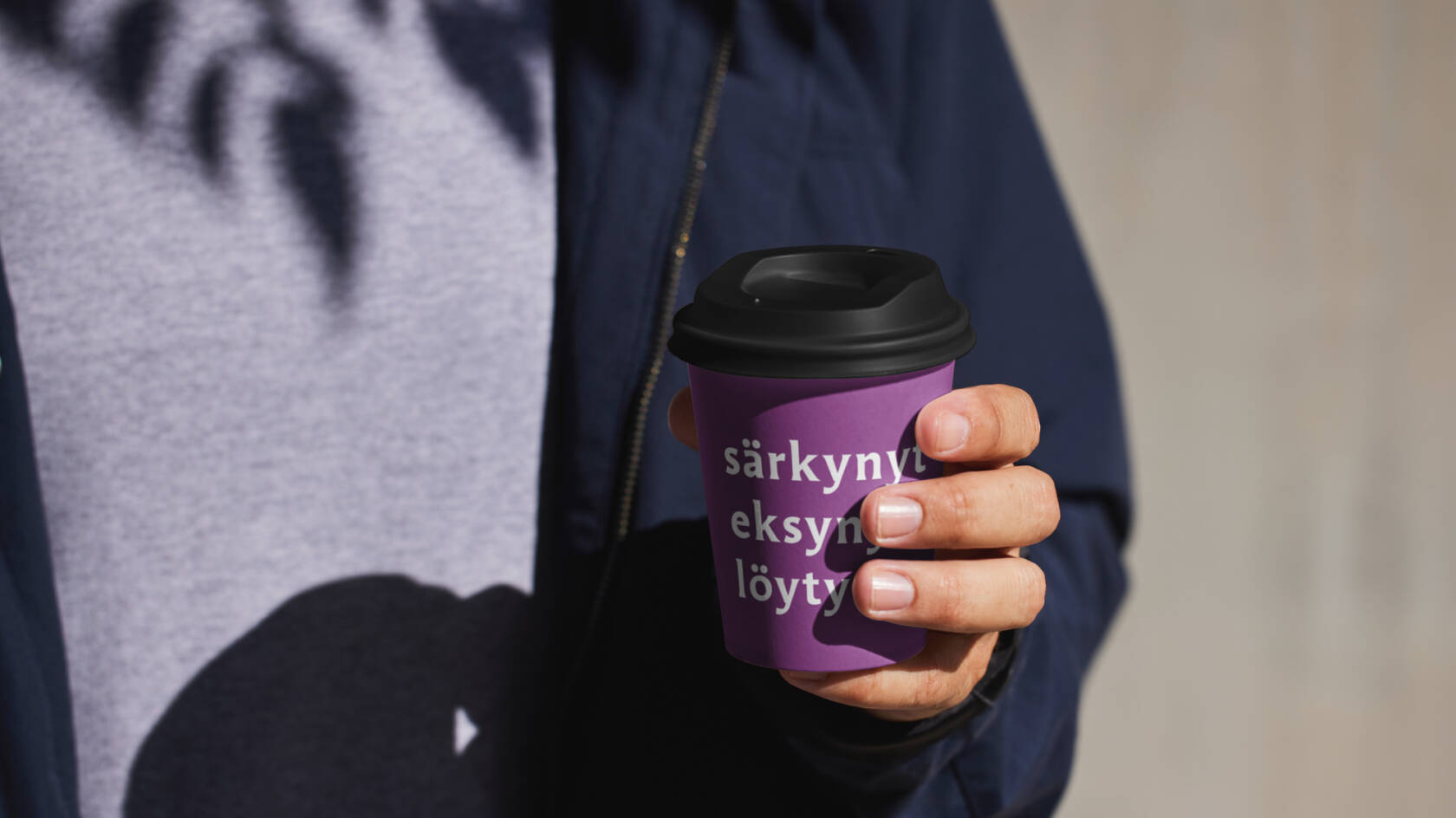 Pahvinen kahvimuki ihmisen kädessä.