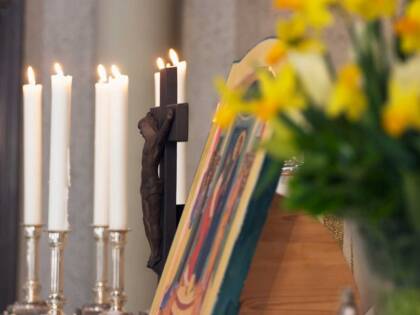 ACandles, a crucifix, and flowers on the Easter altar.