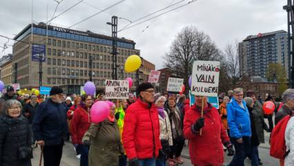 Ihmisiä kyltteineen marssimassa Hämeenkadulla.