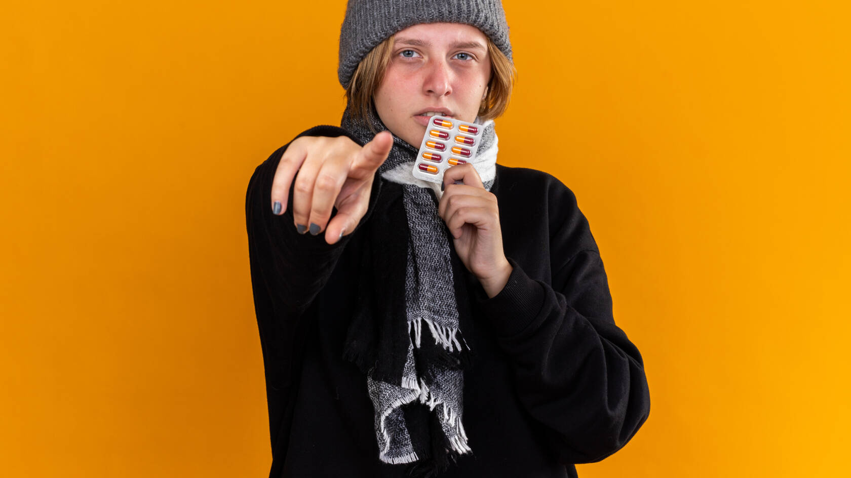 Pipopäinen henkilö, jolla on tablettilevy vasemmassa kädessään, osoittaa oikean käden etusormella katsojaa.