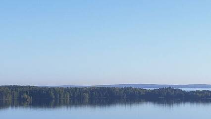 Sinistä taivasta, välissä metsäistä saarta, alareunassa sinistä järveä. Autereinen sininen.