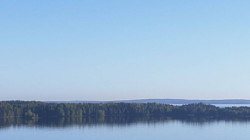 Sinistä taivasta, välissä metsäistä saarta, alareunassa sinistä järveä. Autereinen sininen.