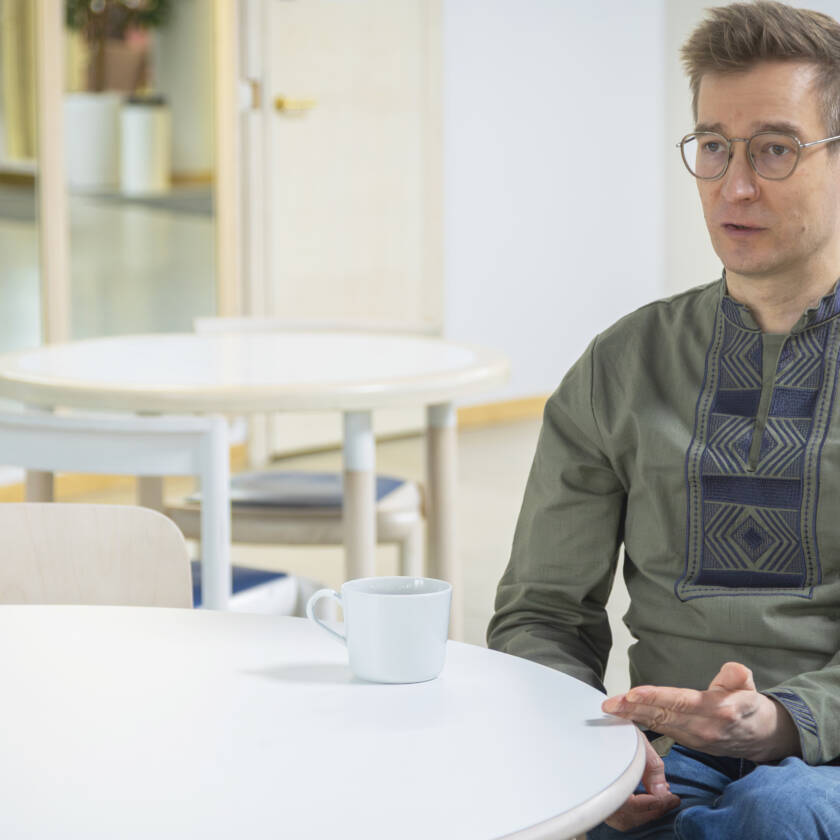 Henkilö istuu pyöreän pöydän ääressä kuppi edessään.