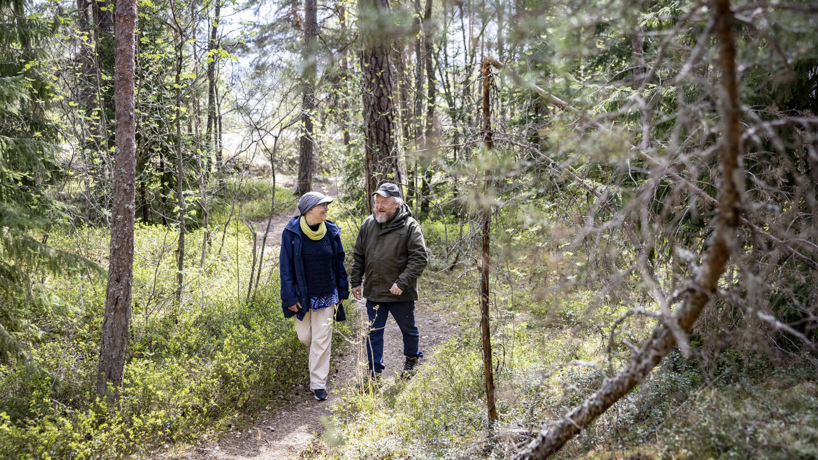 Kaksi ihmistä katsoo toisiinsa kävellessään metsäpolkua.