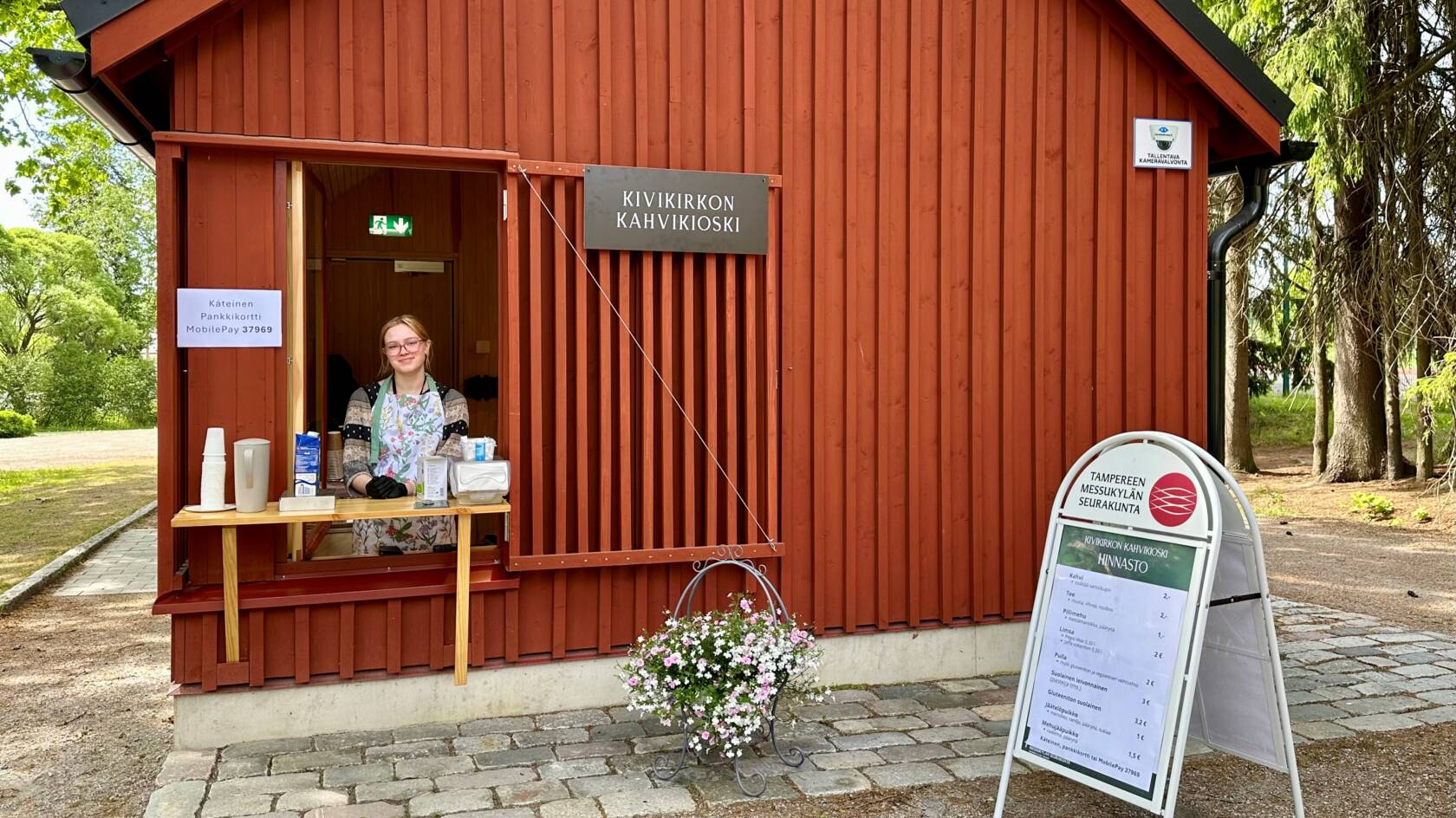 Kivikirkon kahvikioski, luukulla hymyilevä myyjä