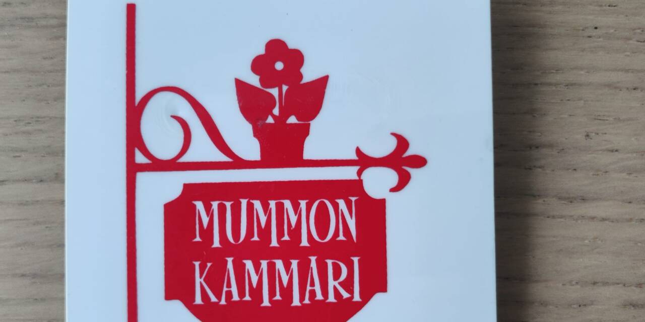 Mummon Kammarin logo rintamerkissä.