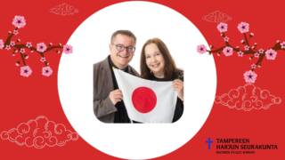 Valkoisen ympyrän keskellä kaksi henkilöä, joilla kädessä Japanin lippu. Punainen pohja, kirsikankukkia.