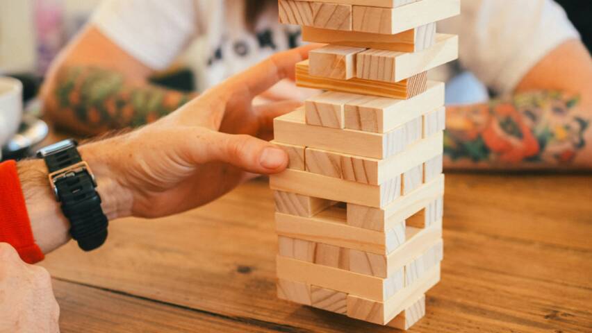 Käsi koskettaa jenga-palaa jenga-tornissa.