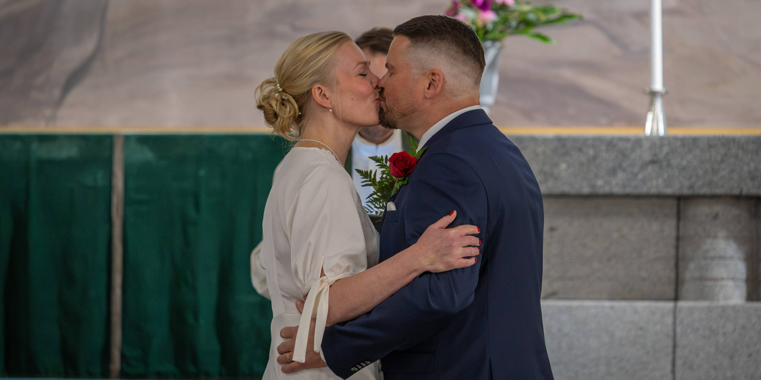Nainen ja mies suutelevat alttarin edessä.